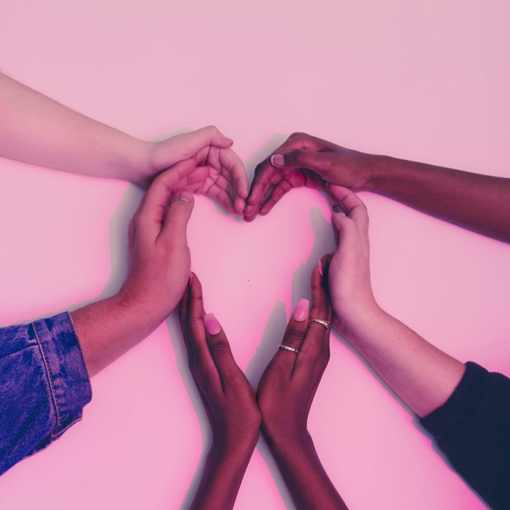 Hands from multiple people forming a heart shape